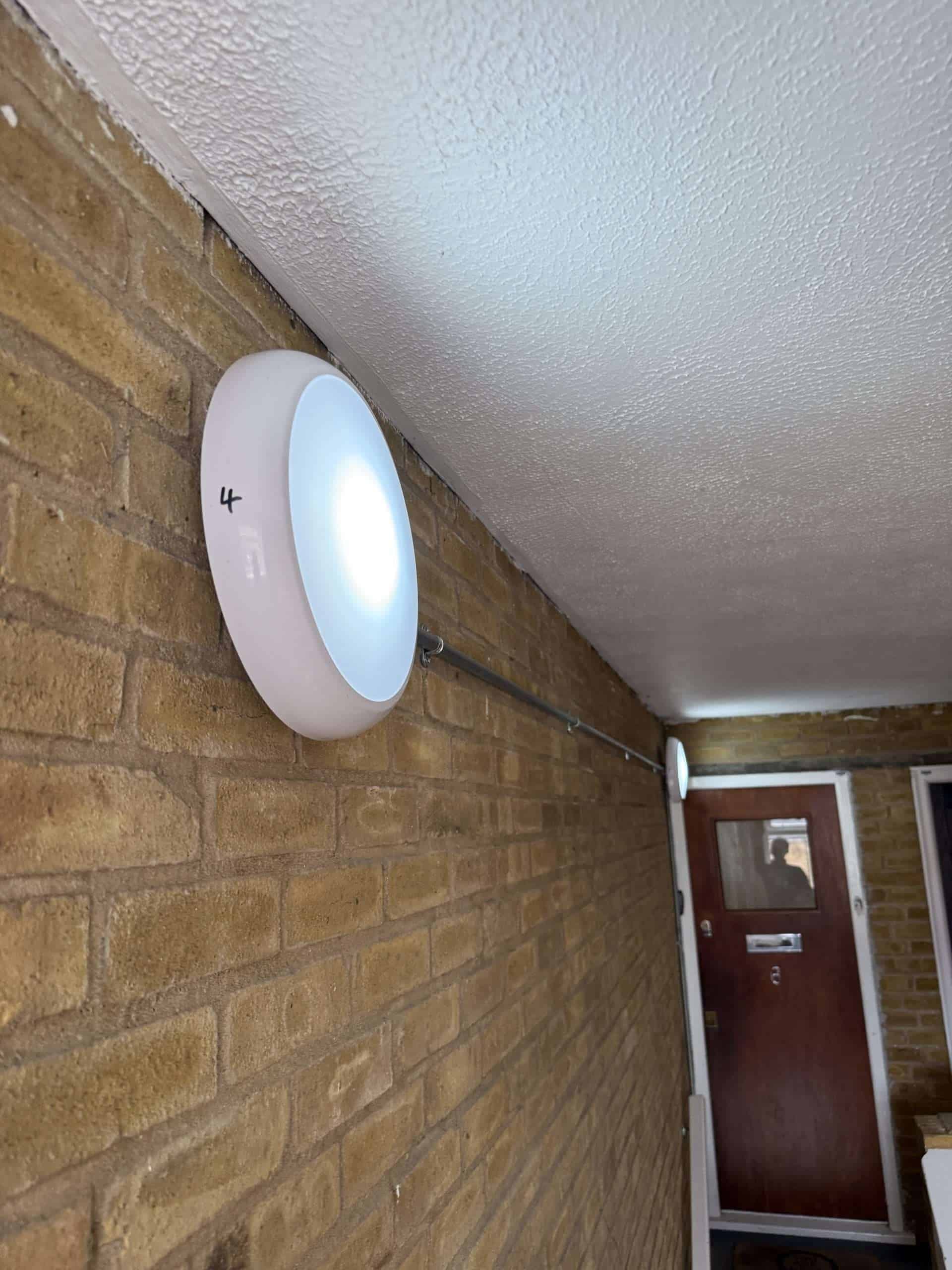 Modern outdoor wall light fixture attached to brick wall for property lighting.
